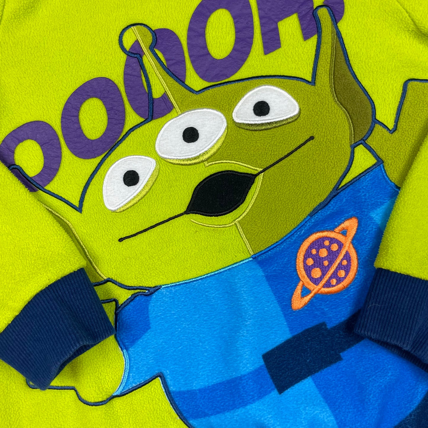 Grüner Kinderpullover mit Toy-Story-Alien-Print und dunkelblauen Bündchen, Größe ca. 116. – detail