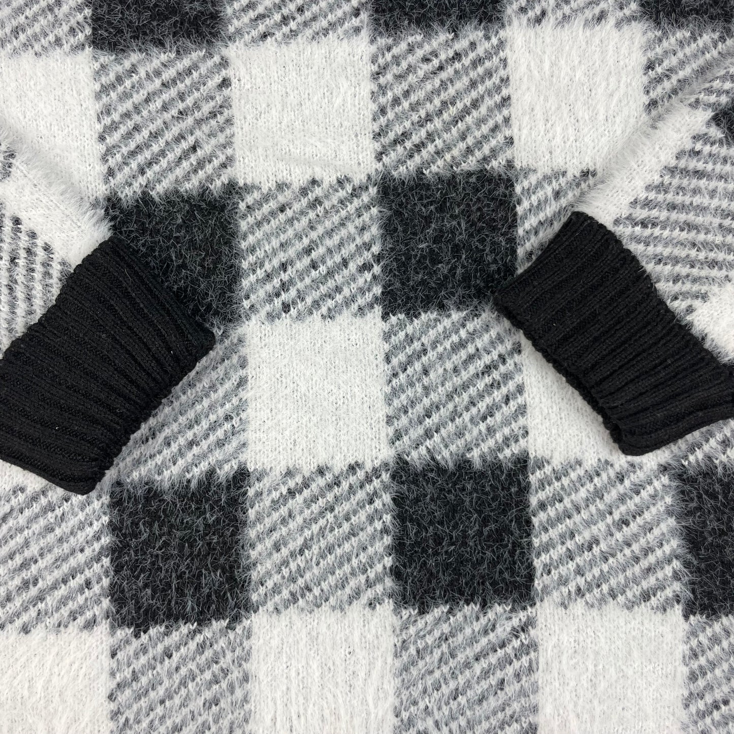 Flauschiger Kinderpullover mit schwarz-weißem Karomuster, Rundhals und Rippbündchen – detail