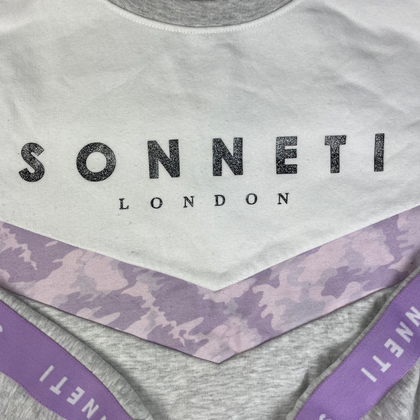 Graues Sweatshirt mit weißer Brustpartie und lilafarbenen Sonneti-Details, Größe 10–12 Jahre – detail