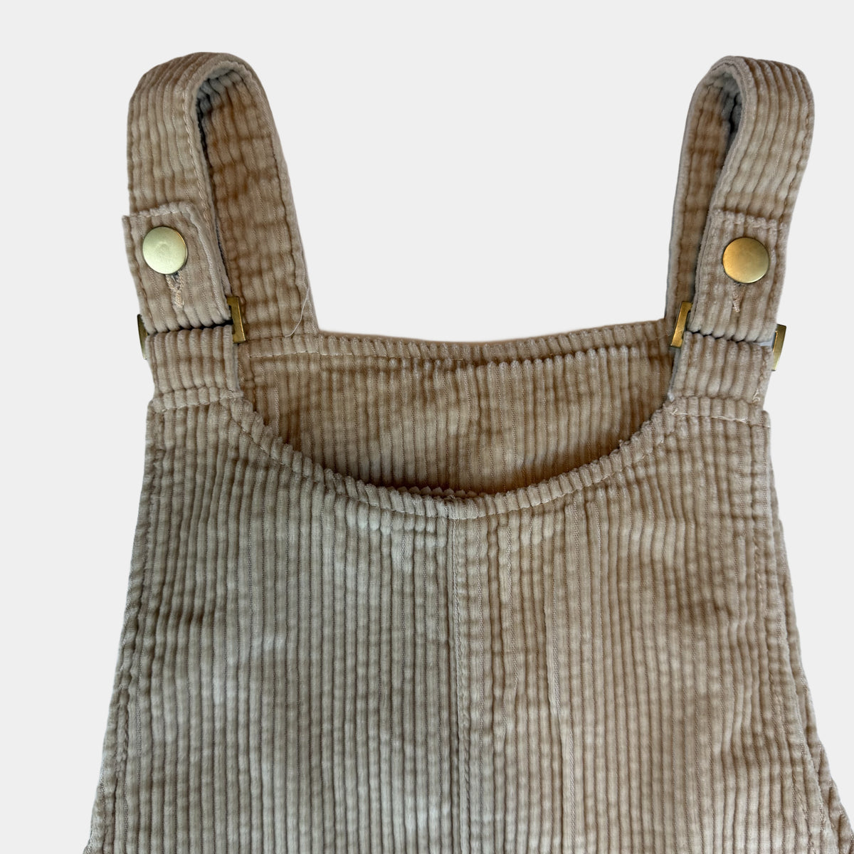 Beiges Cord-Latzkleid für Kinder mit Knopfträgern und seitlichen Taschen – detail