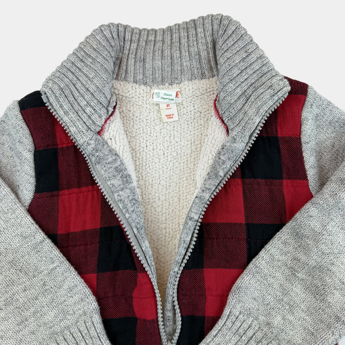 Rote und schwarze karierte Kinder-Strickjacke mit grauen Ärmeln und Reißverschluss – close‑up