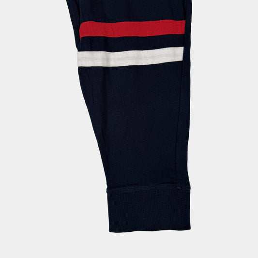 Dunkelblaue Kinder-Jogginghose mit Bindeband und rot-weißem Streifen am Bein – close‑up
