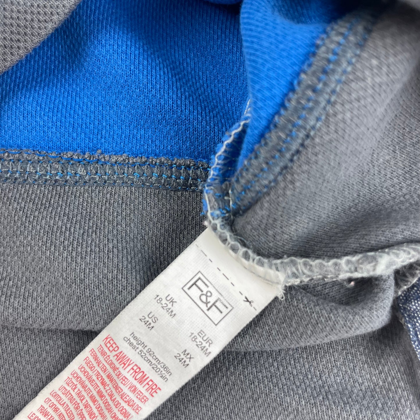 Grauer Kinderpullover mit blauem Streifen und 77-Aufdruck. – label