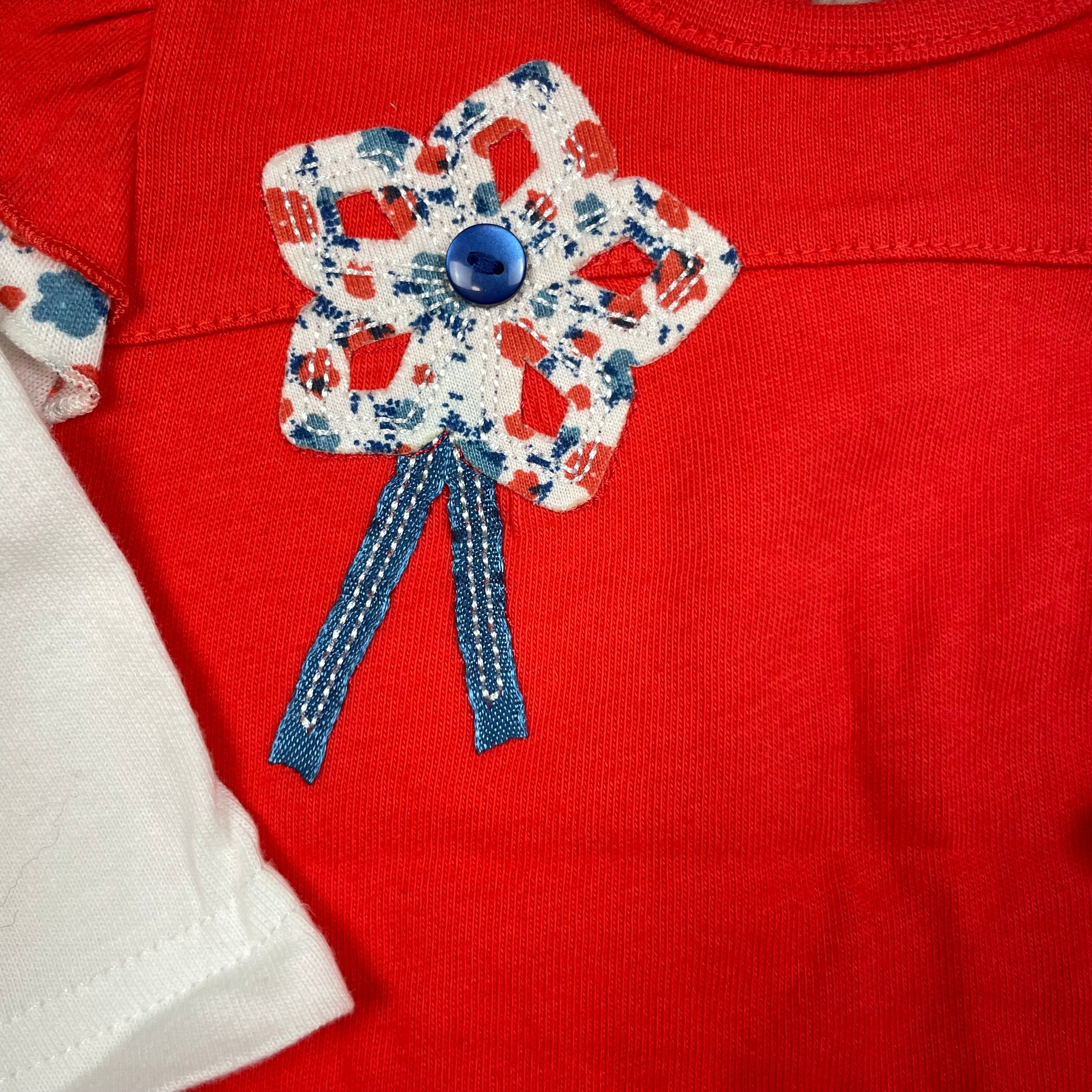 Rotes Baby-Kleid von M&Co mit weißen langen Ärmeln, Blumenapplikation und Rüschen-Saum – detail