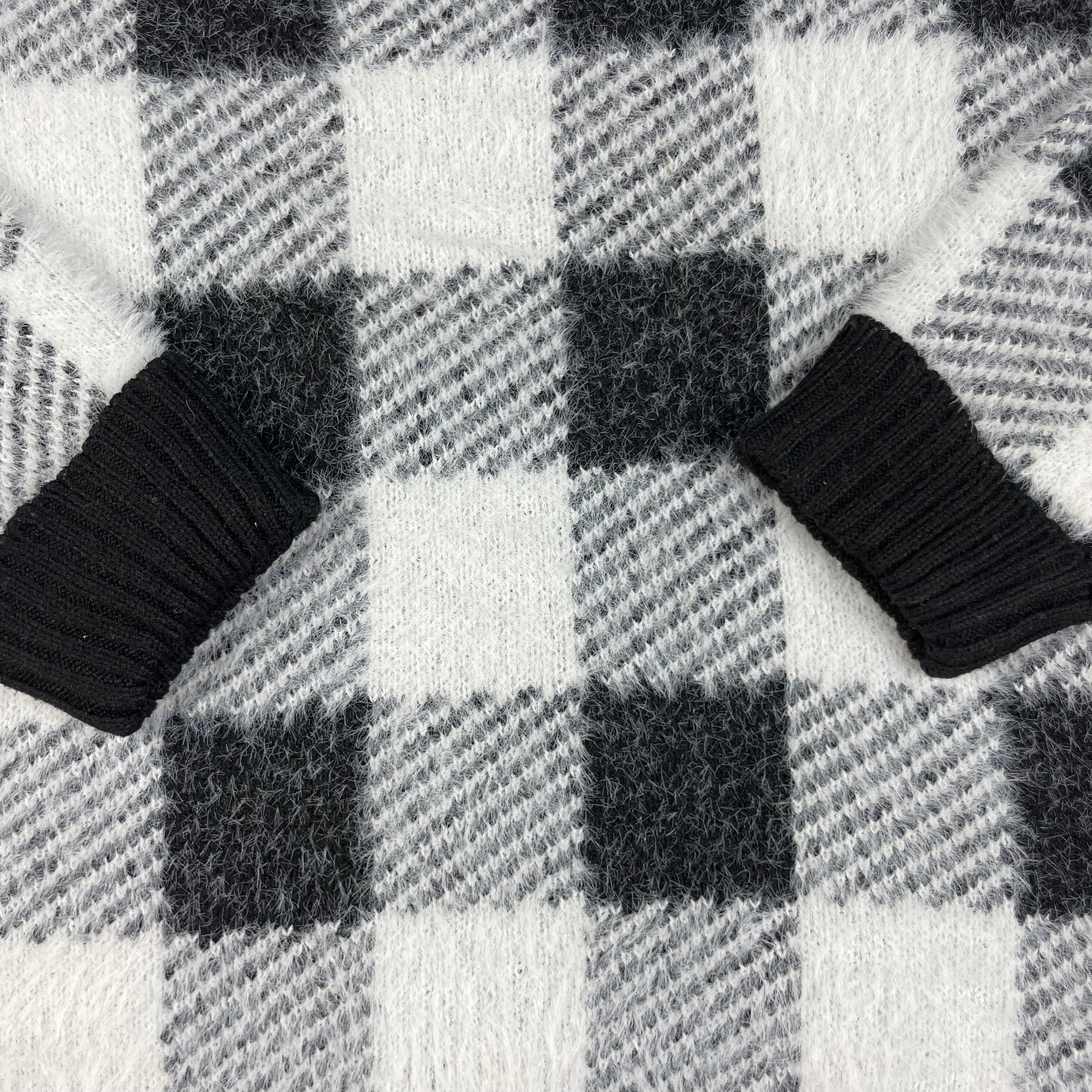 Flauschiger Kinderpullover mit schwarz-weißem Karomuster, Rundhals und Rippbündchen – detail