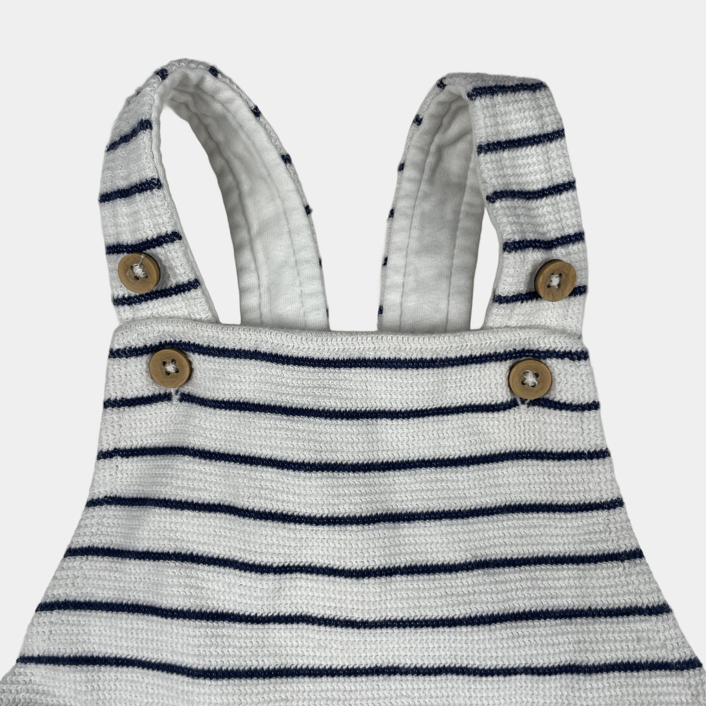 Gestreifter weißer und dunkelblauer Baby-Overall mit Knöpfen an den Trägern – detail