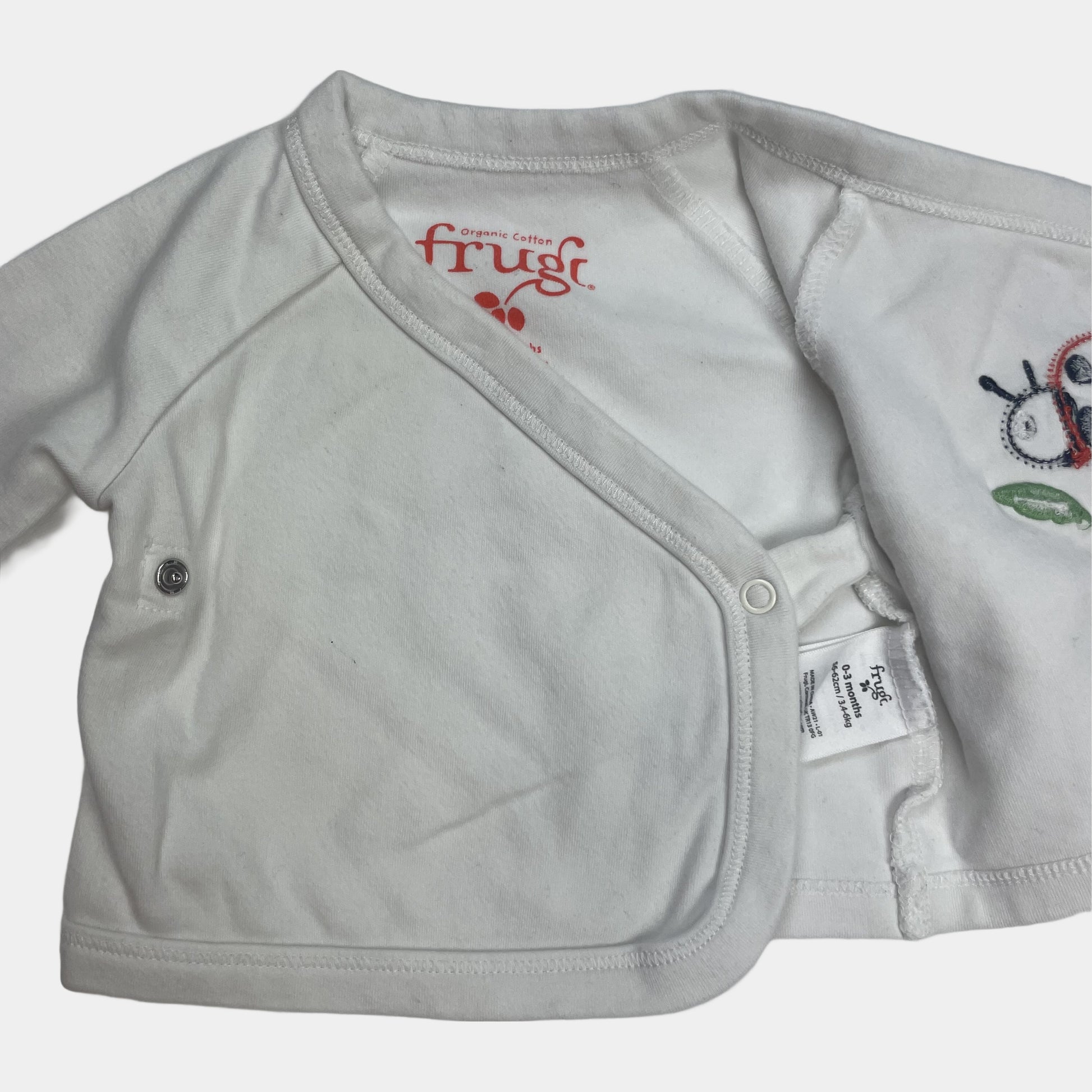 Weißer Baby-Kimono mit Marienkäfer-Applikation auf der Vorderseite – flatlay