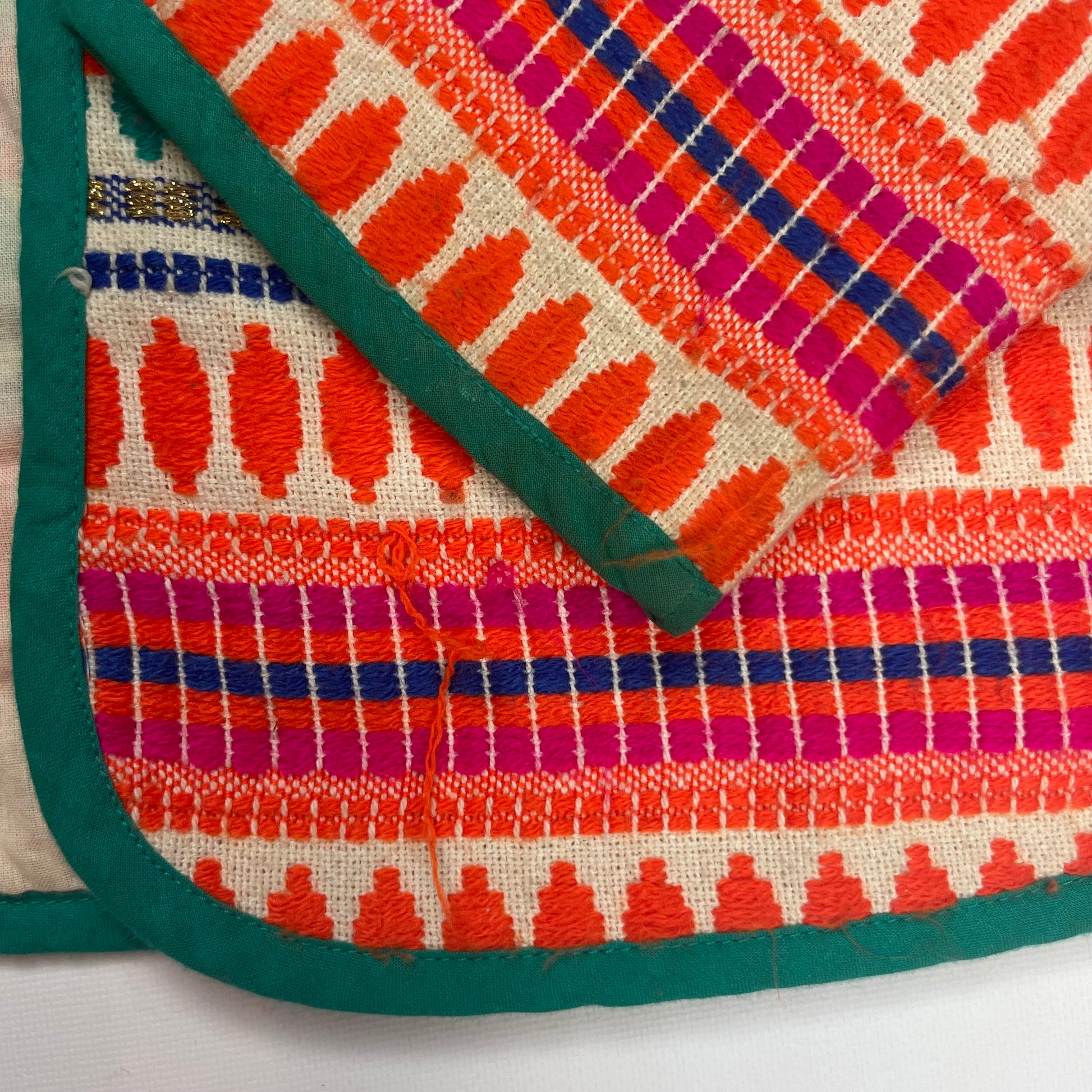 Bunte Strickjacke mit Ethnomuster und grüner Umrandung – detail