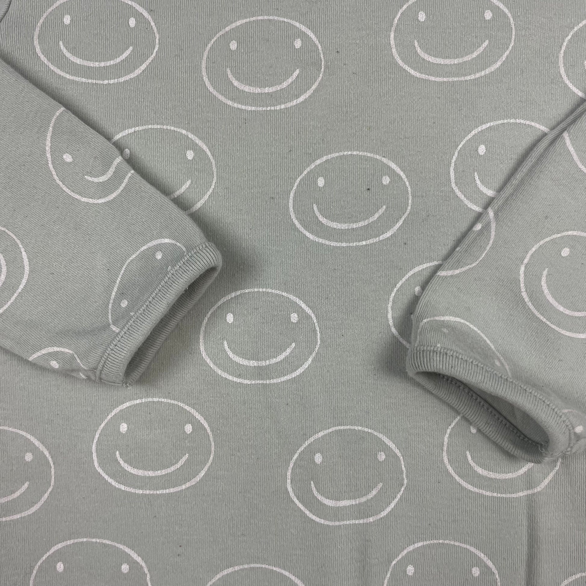 Grauer Pullover mit lächelnden Smileys als Muster – detail