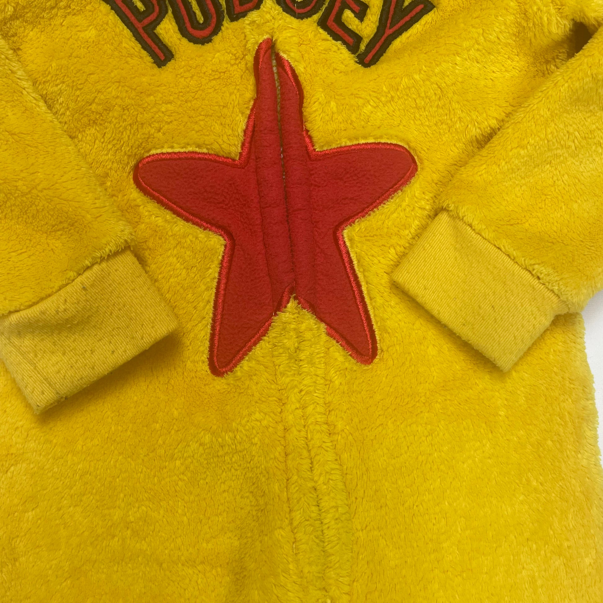 Gelber Overall mit Sternmotiv und bunten Punkten. – close‑up