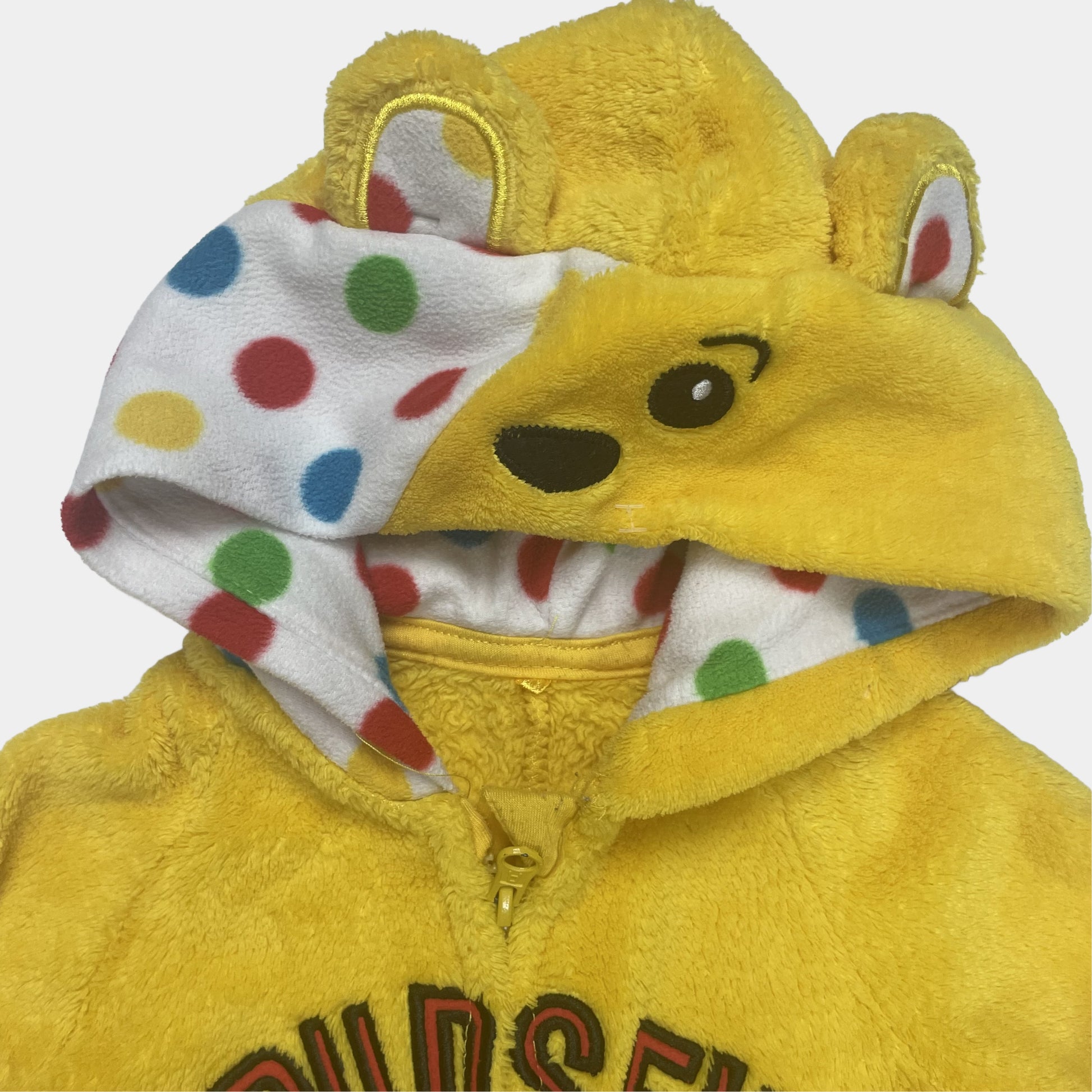 Gelber Overall mit Sternmotiv und bunten Punkten. – detail