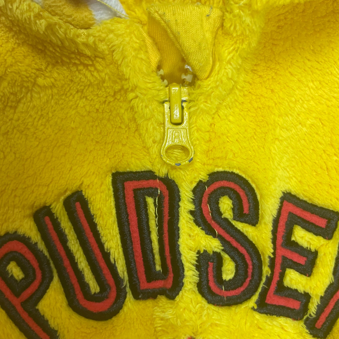 Gelber Overall mit Sternmotiv und bunten Punkten. – zip