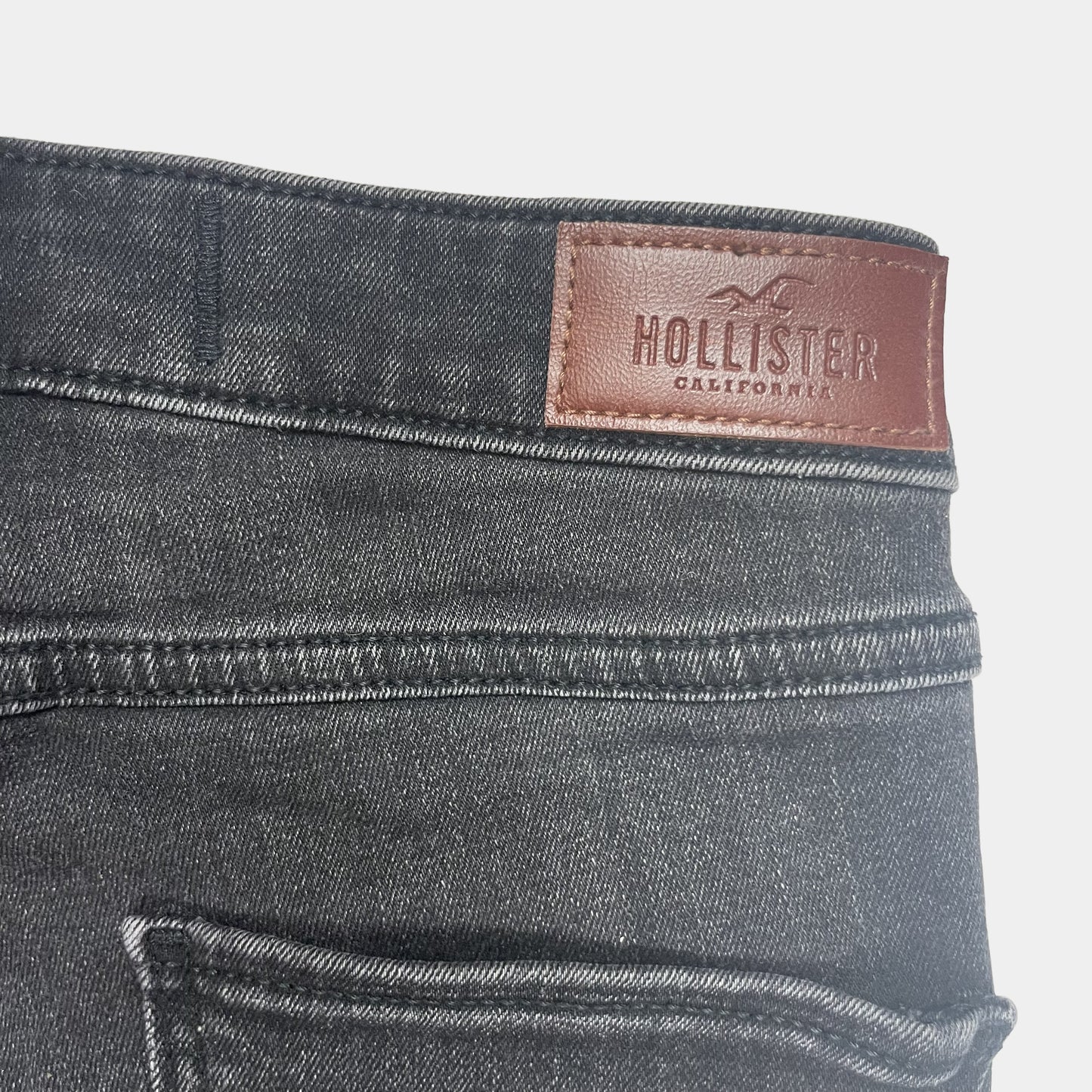 Graue Denim-Jeans mit schmaler Passform und klassischen Gürtelschlaufen. – label