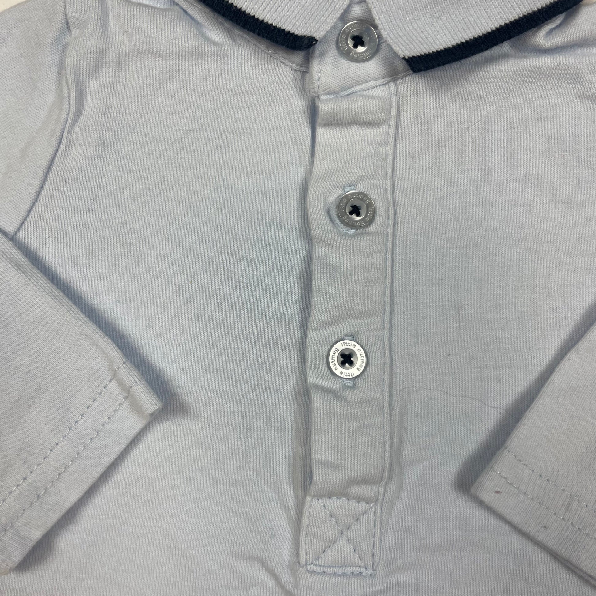Hellblaues Langarm-Poloshirt mit Knopfleiste und schwarzem Streifen am Kragen. – detail