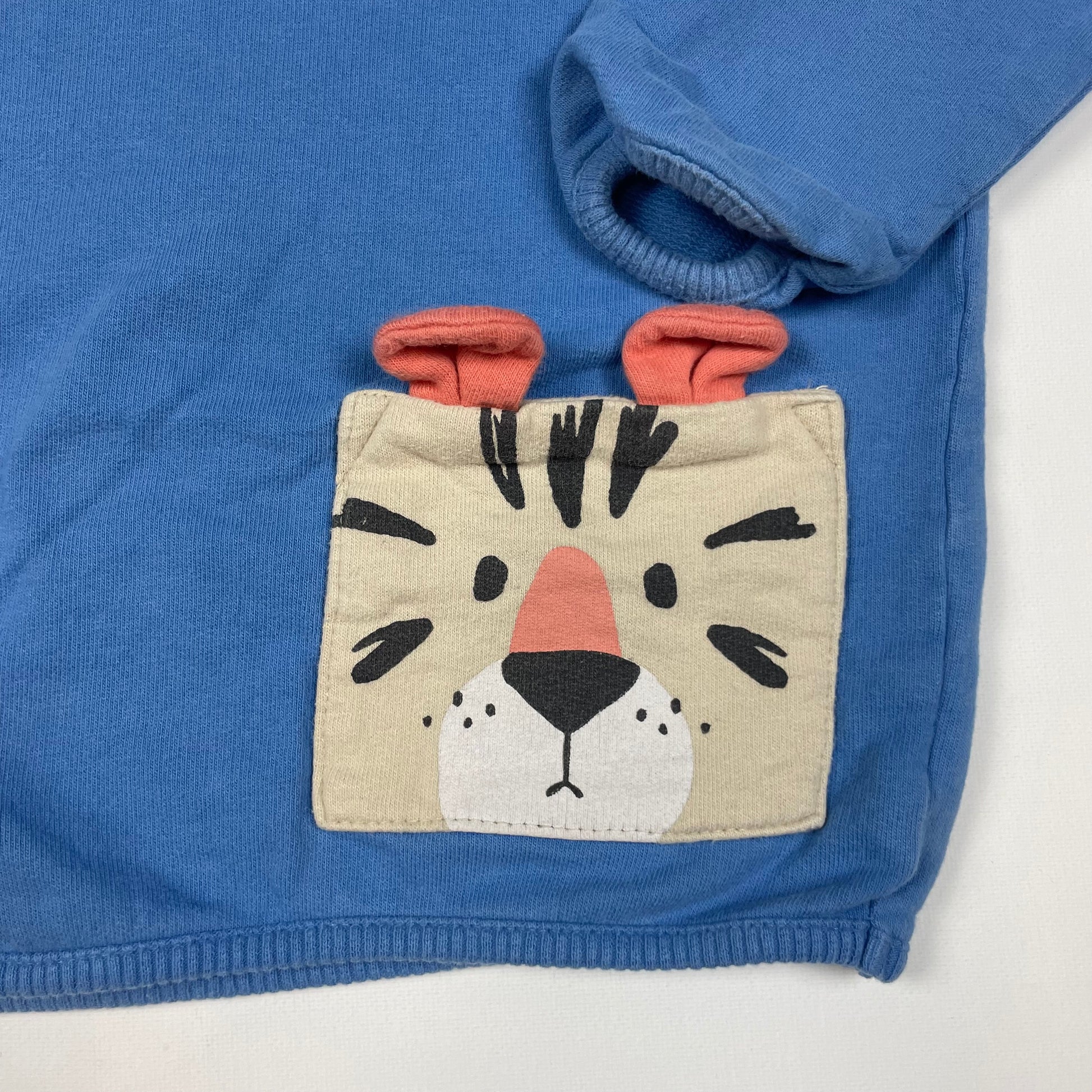 Blauer Pullover mit Tiger-Tasche und Knöpfen seitlich. – detail