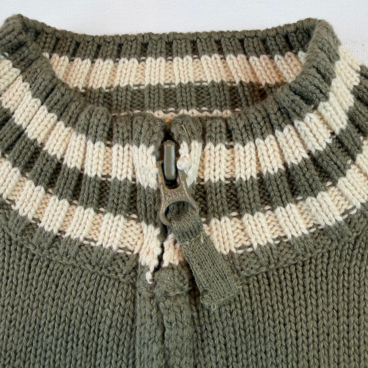 Olivgrüne Kinder-Strickjacke aus Baumwolle mit Reißverschluss und gestreiften Bündchen – detail