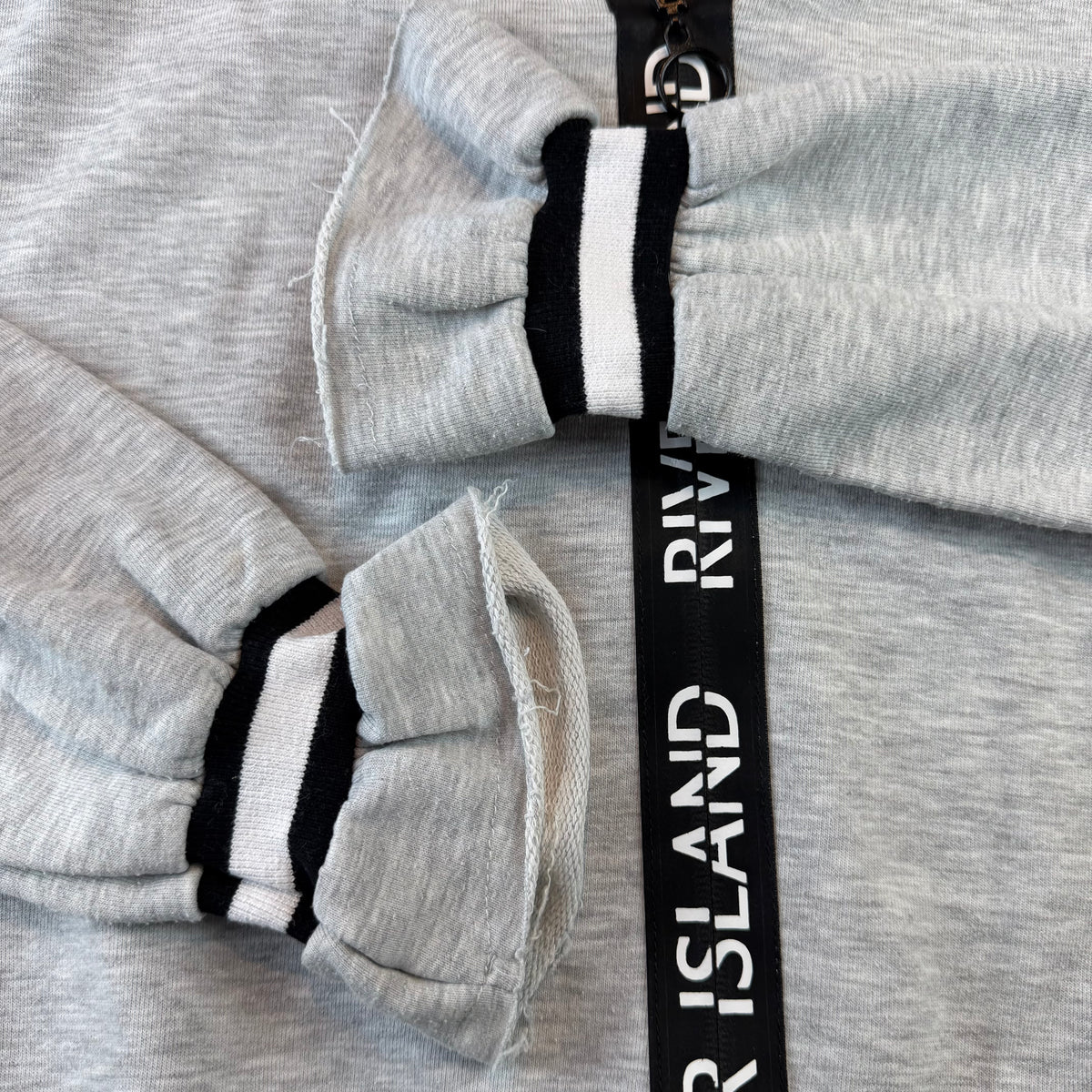 Grauer Kinder-Kapuzenpullover mit Reißverschluss und River-Island-Schriftband – detail
