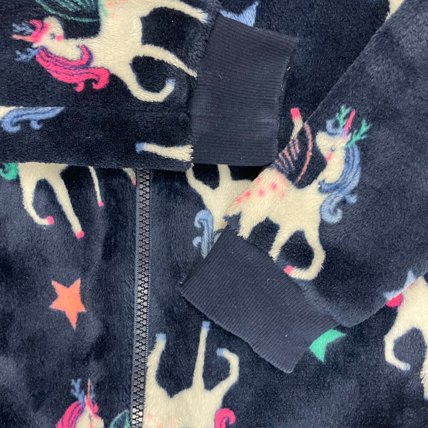 Ein dunkelblauer Overall mit Einhornmuster und Kapuze mit Horn und Mähne. – close‑up