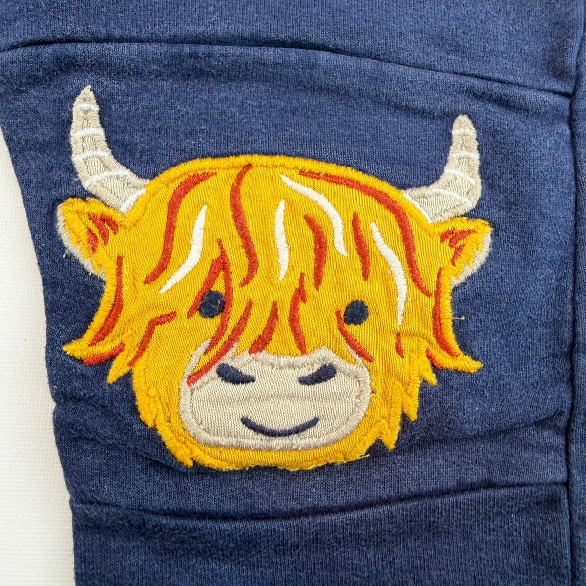 Dunkelblaue Kinder-Sweathose mit Kuh-Stickereien auf den Knien – detail