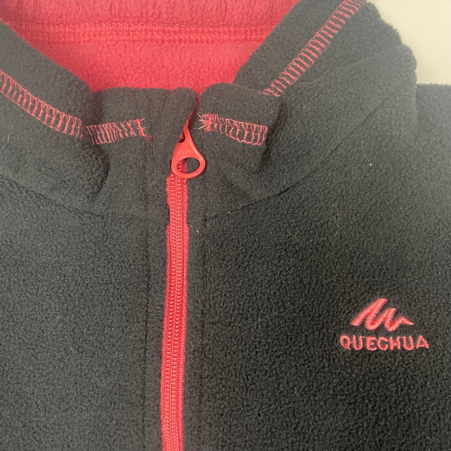 Schwarzes Fleece-Pullover mit Reißverschluss und roten Details.
