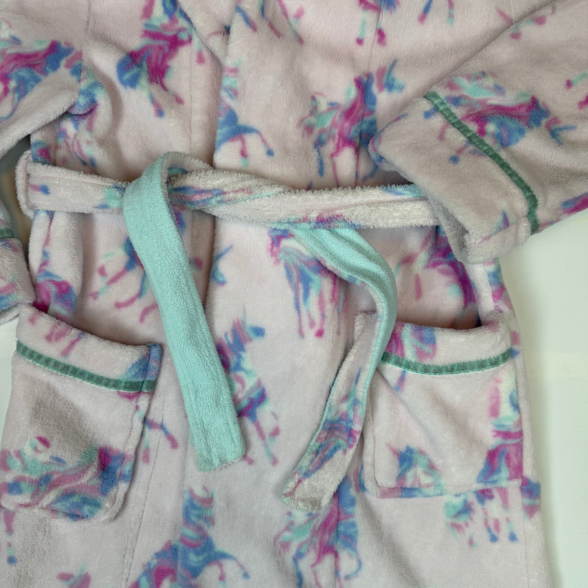 Rosa Fleece-Bademantel für Kinder mit Kapuze, Bindegürtel, Taschen und Einhornmuster – close‑up