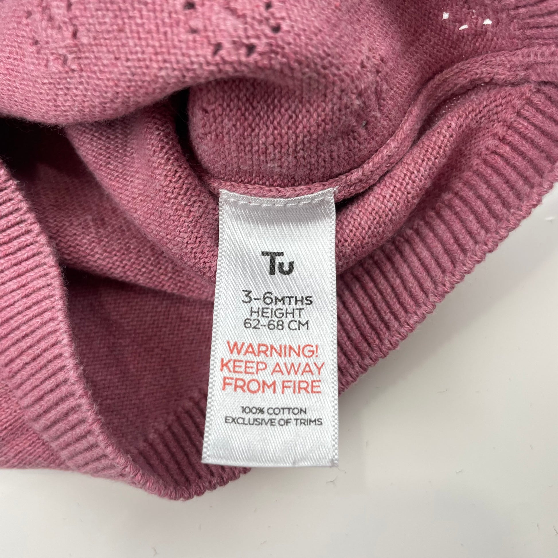 Lilafarbene Strickjacke für Babys mit Rüschen an den Schultern. – label
