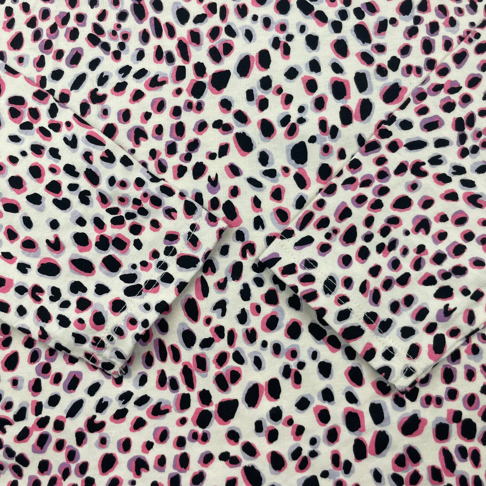 Langarmshirt mit Punkte-Muster in Rosa und Schwarz auf weißem Hintergrund. – detail