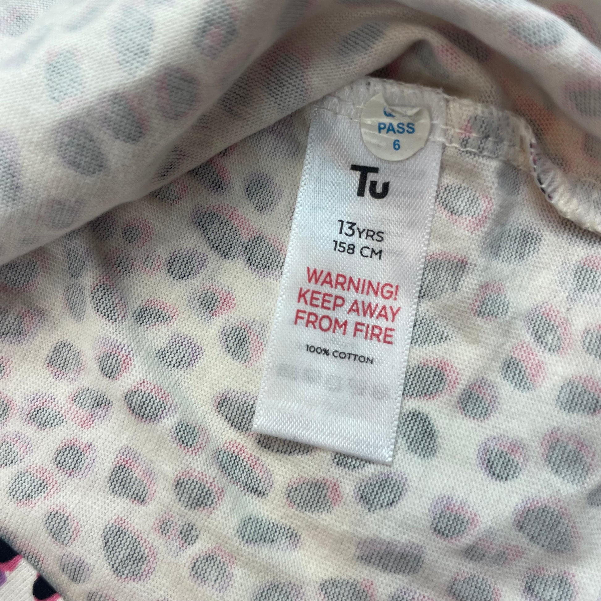 Langarmshirt mit Punkte-Muster in Rosa und Schwarz auf weißem Hintergrund. – label