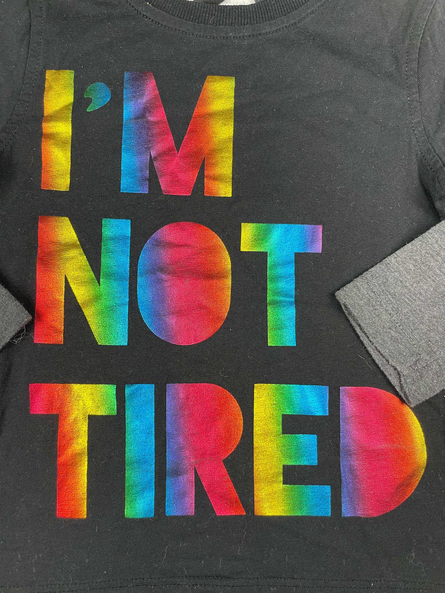 Schwarzes Langarmshirt mit grauen Ärmeln und buntem Schriftzug I'M NOT TIRED von George, Größe 1–1,5 Jahre – detail
