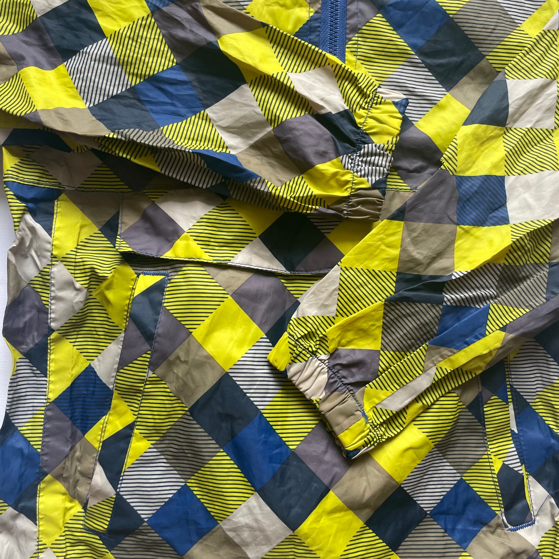 Mehrfarbige Regenjacke mit Kapuze und quadratischem Muster – detail