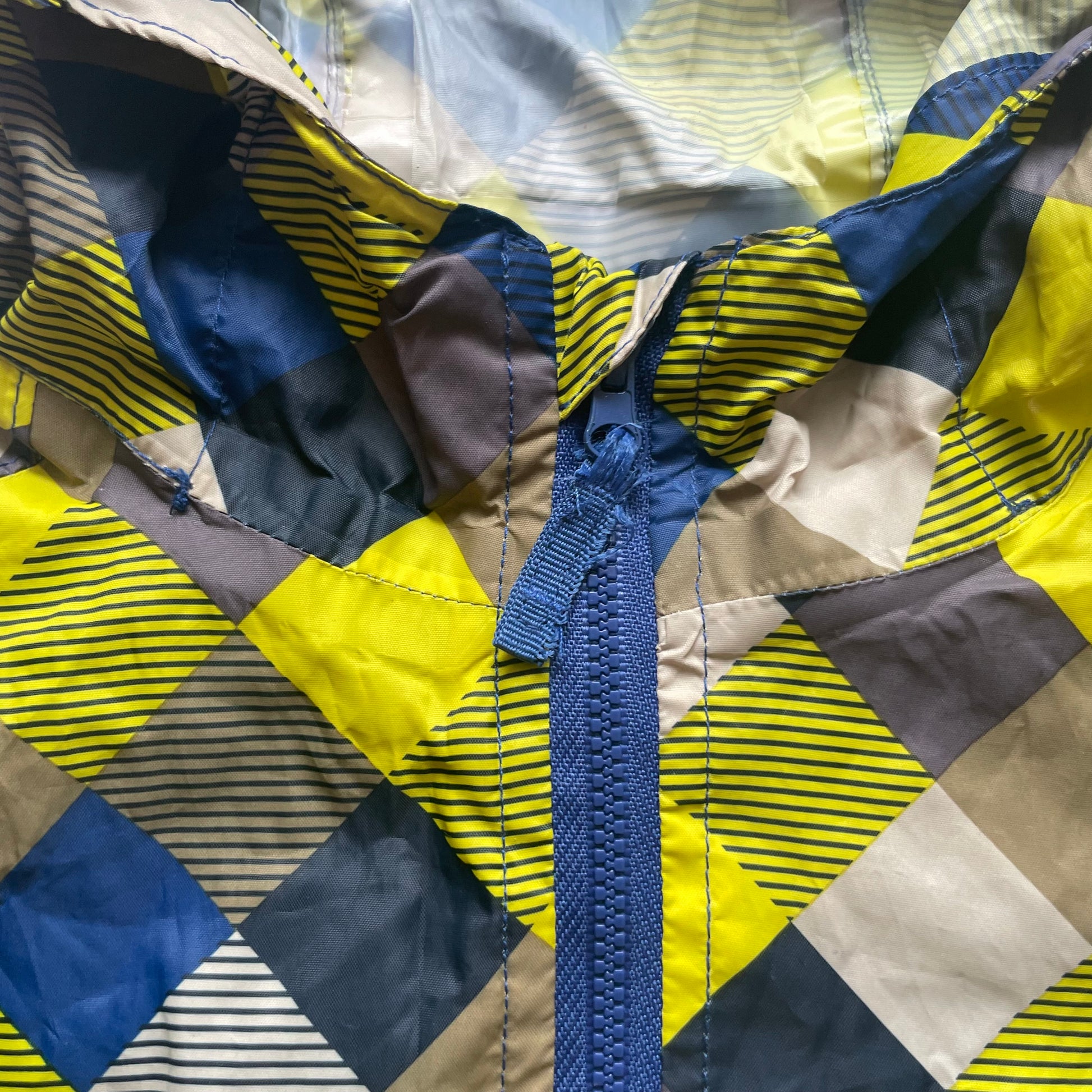 Mehrfarbige Regenjacke mit Kapuze und quadratischem Muster – zip