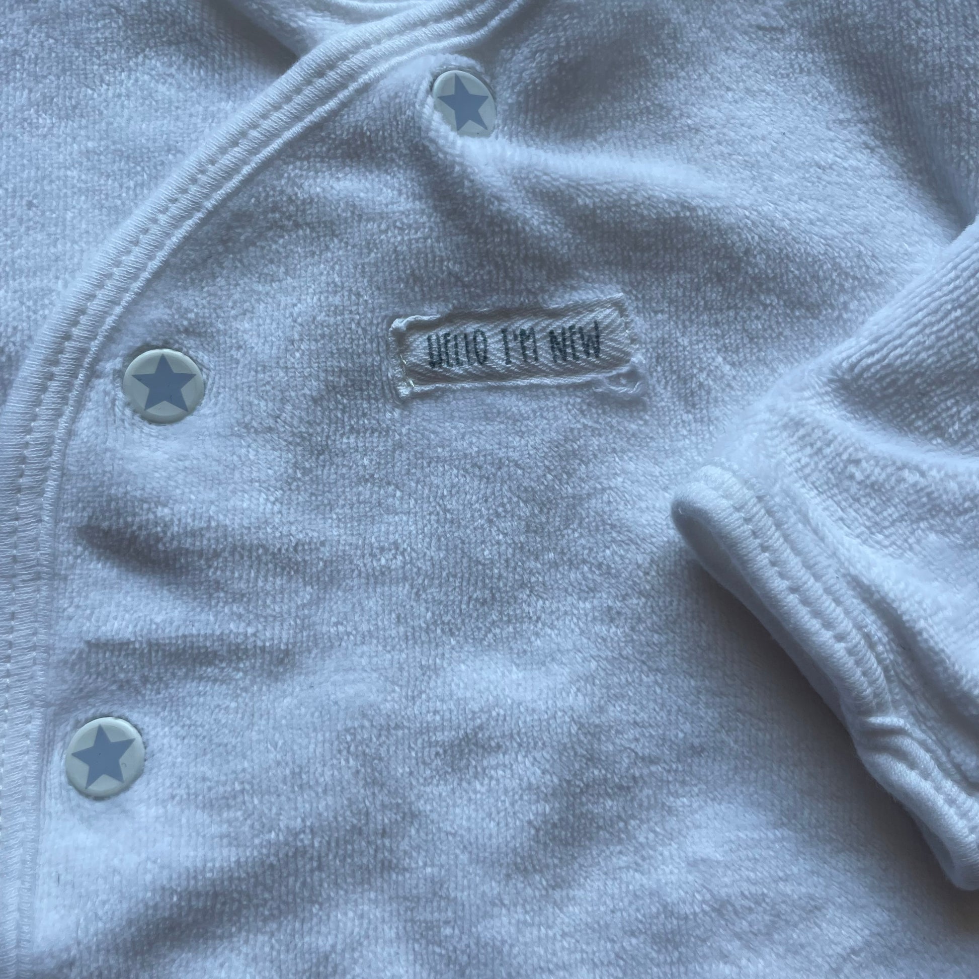 Weiße Strickjacke aus weichem Material mit Knöpfen und langen Ärmeln. – detail