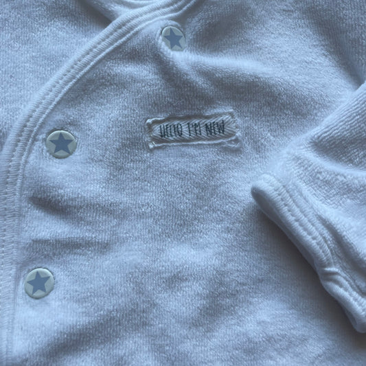 Weiße Strickjacke aus weichem Material mit Knöpfen und langen Ärmeln. – detail