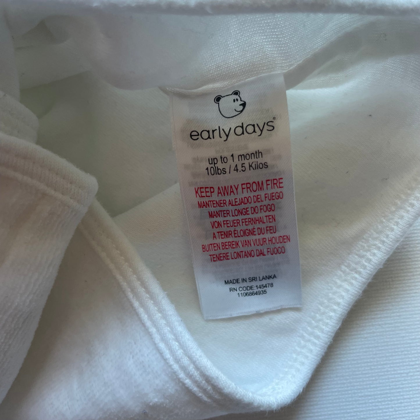 Weiße Strickjacke aus weichem Material mit Knöpfen und langen Ärmeln. – label