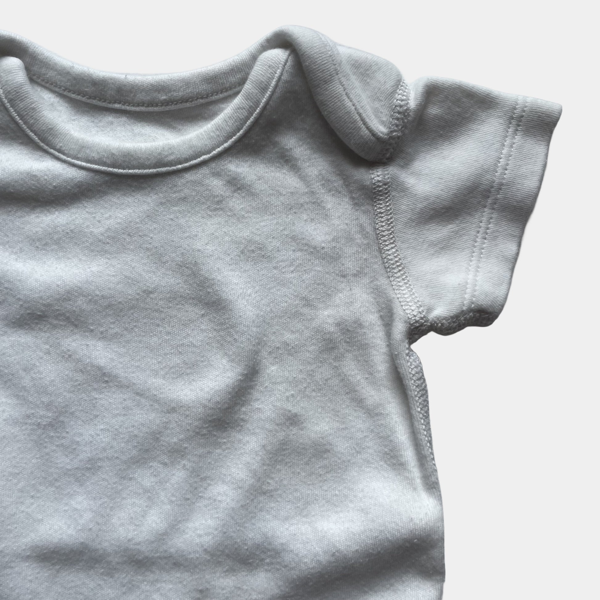 Weißer Babybody aus Baumwolle mit kurzen Ärmeln und Druckknöpfen im Schritt. – detail