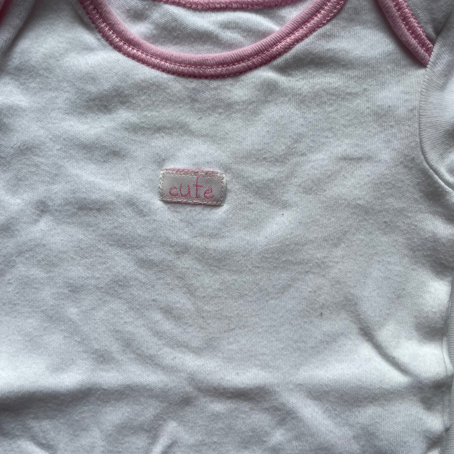 Weißer Babybody von George mit rosa Paspeln. – detail