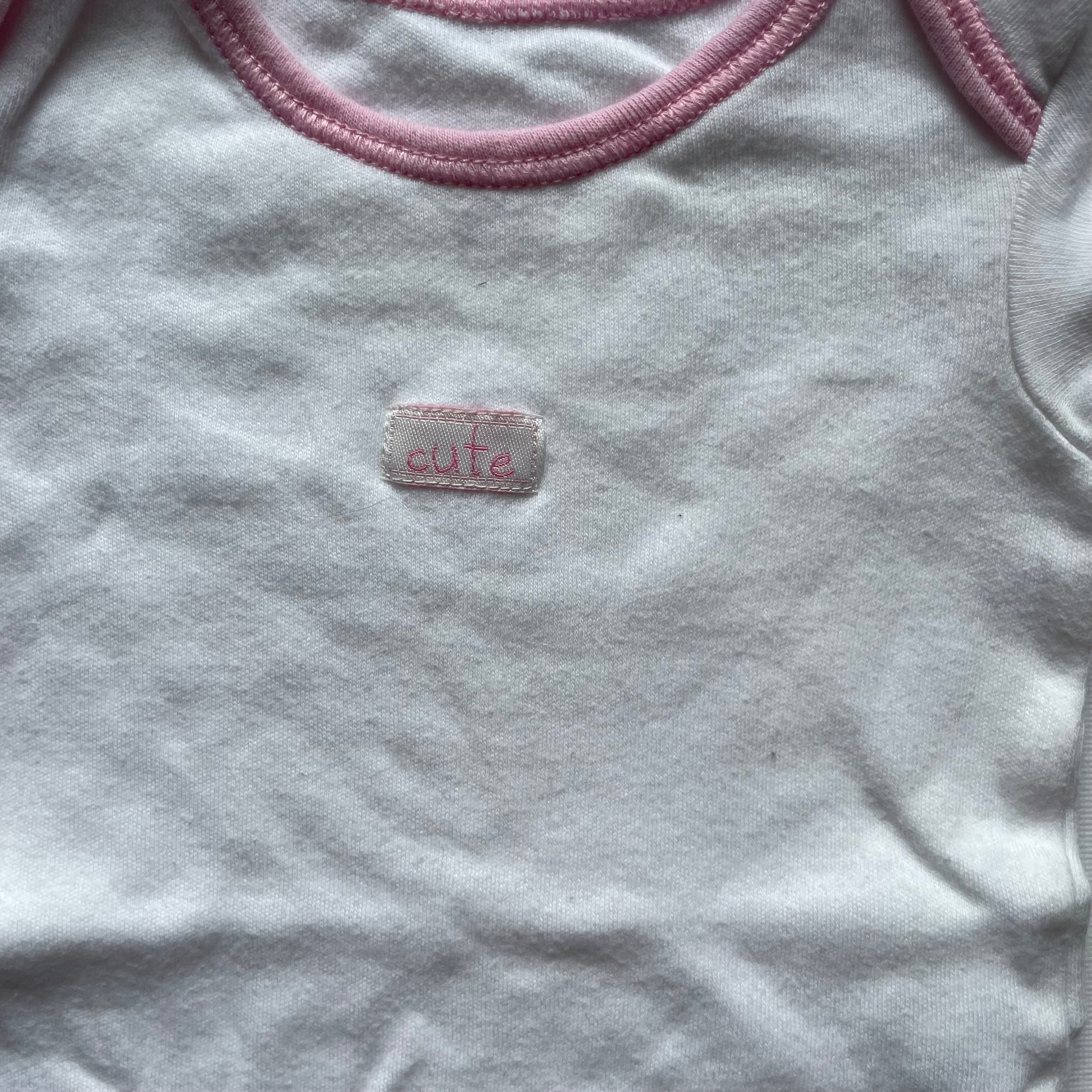 Weißer Babybody von George mit rosa Paspeln. – detail