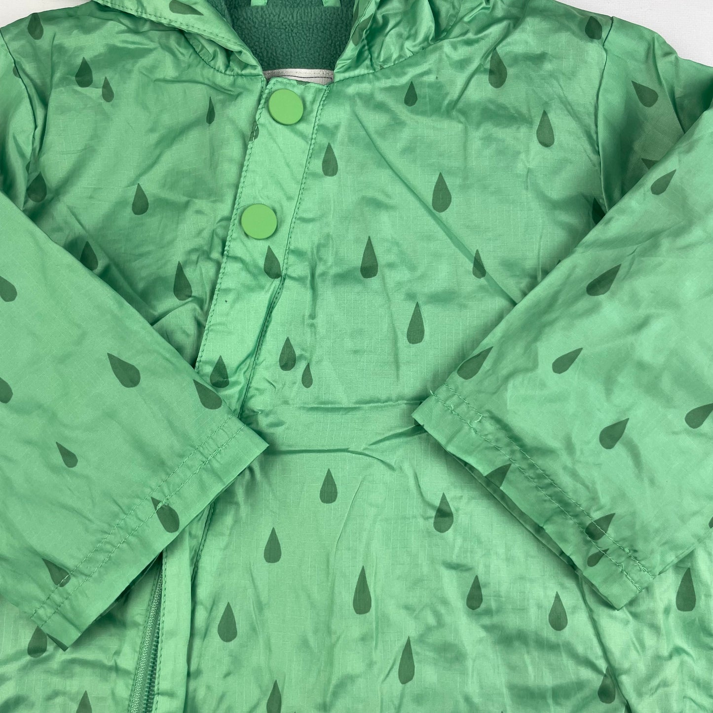 Grüner Regenanzug mit Kapuze und Tropfenmuster für Babys. – detail