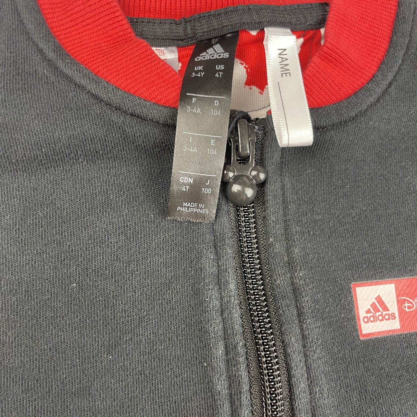 Schwarze Jacke mit roten Akzenten und Disney-Logo – detail