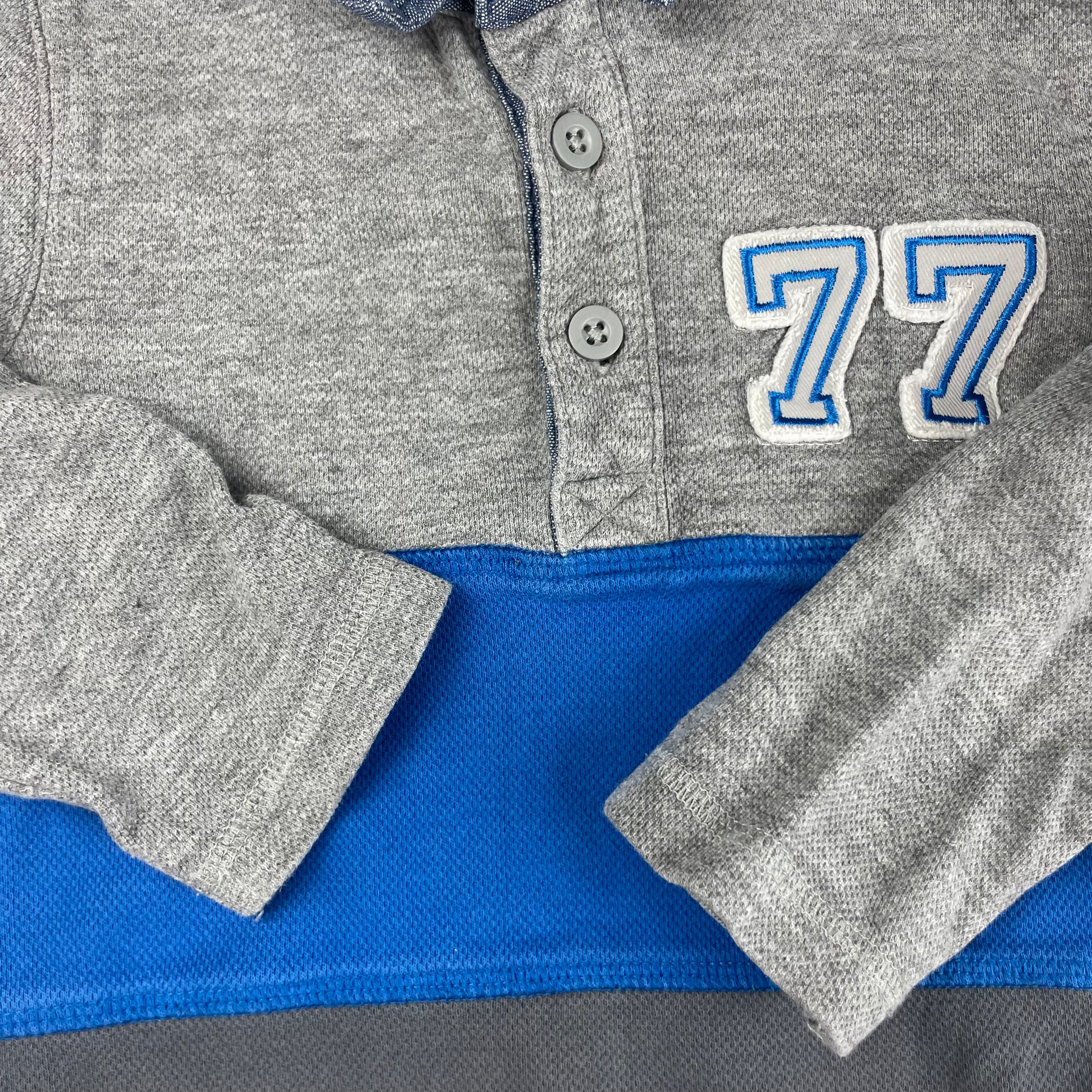 Grauer Kinderpullover mit blauem Streifen und 77-Aufdruck. – detail