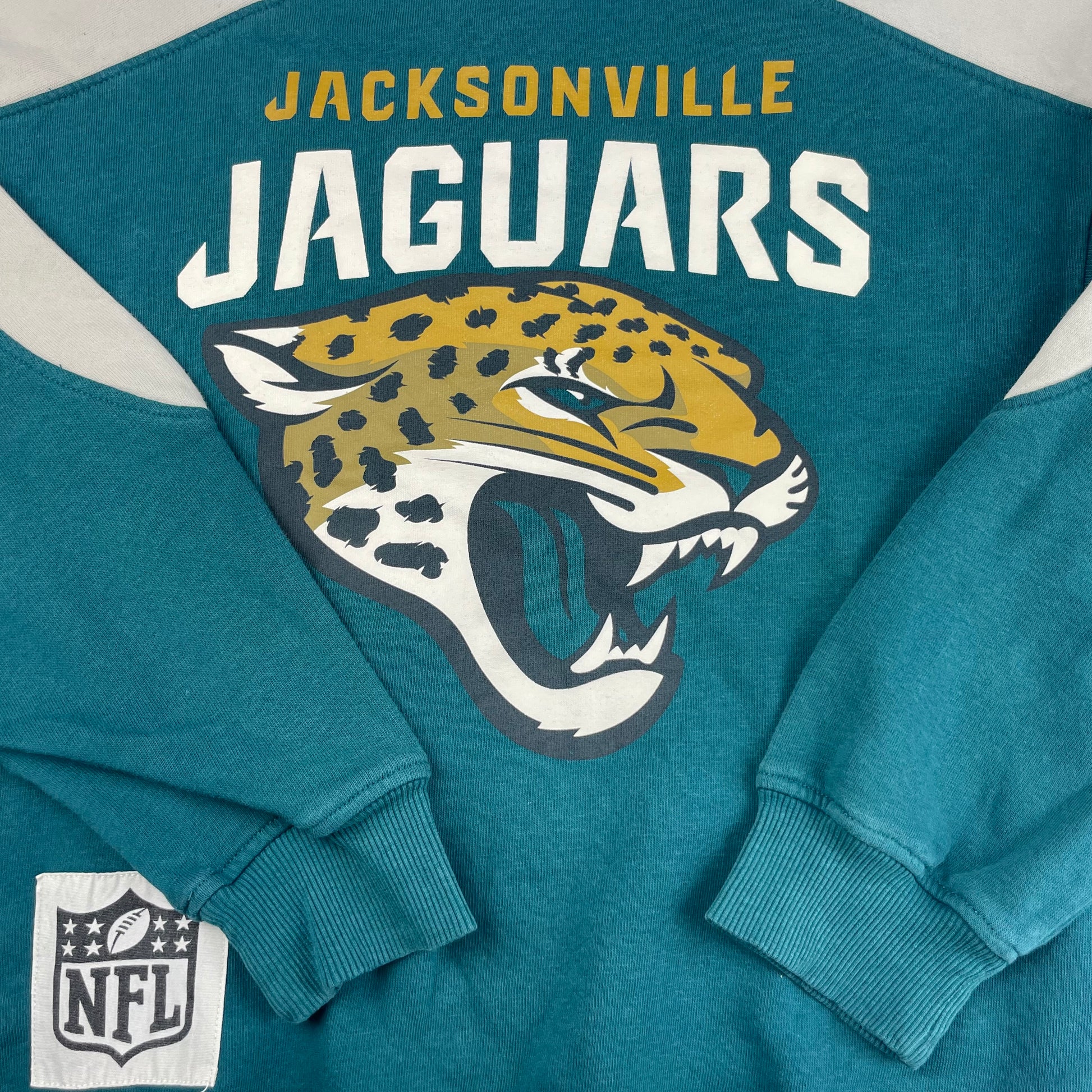 Grünes NFL Sweatshirt mit "Jacksonville Jaguars"-Logo und abgesetzten hellen Ärmeln. – detail